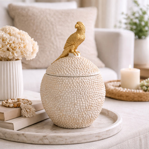 Chic et originale, cette boîte ronde blanche ornée d’un perroquet doré est un véritable objet décoratif qui attire tous les regards. Son contraste élégant entre le blanc lumineux et la finition dorée apporte une touche exotique et raffinée à votre intérieur.