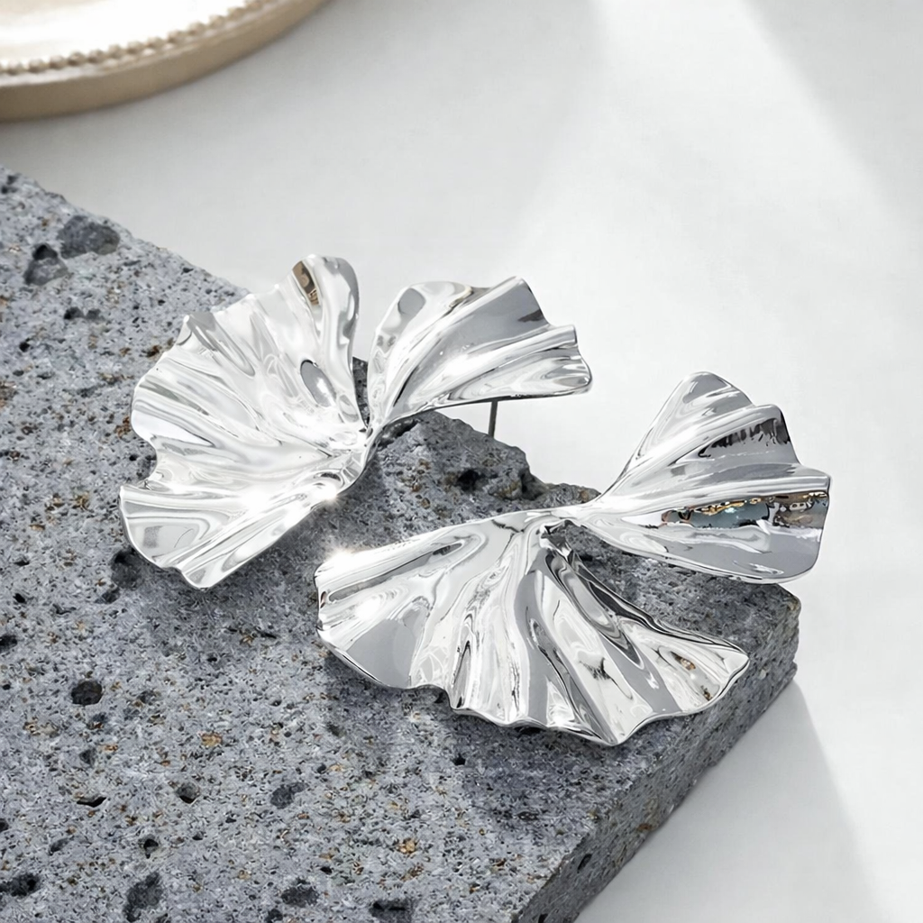 Inspirées de la délicatesse végétale, ces boucles d’oreilles argentées reprennent la silhouette emblématique de la feuille de ginkgo dans une version sculptée et lumineuse. Leur surface ondulée capte subtilement la lumière et apporte du relief à l’ensemble.